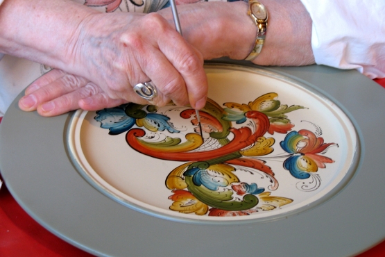 Мастерица украшает блюдо традиционной норвежской живописью – росемалингом 